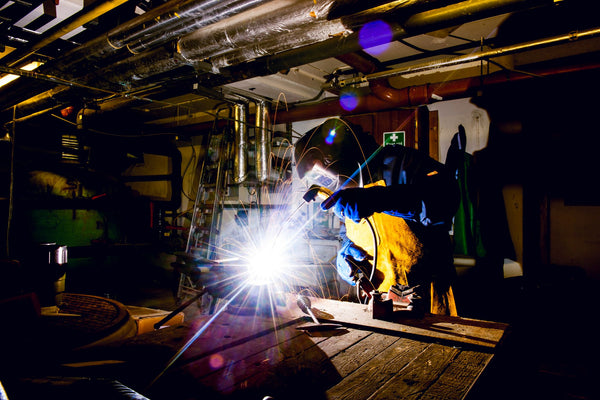 Image: Welder in protective gear operating welding equipment
